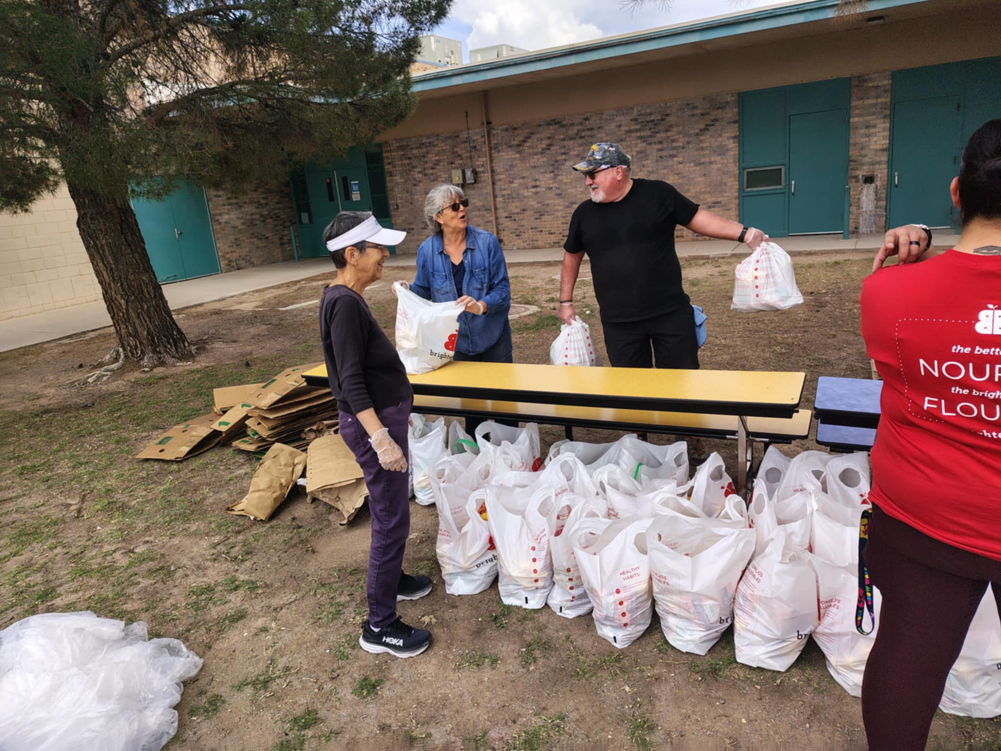 three person organizing produce in bags