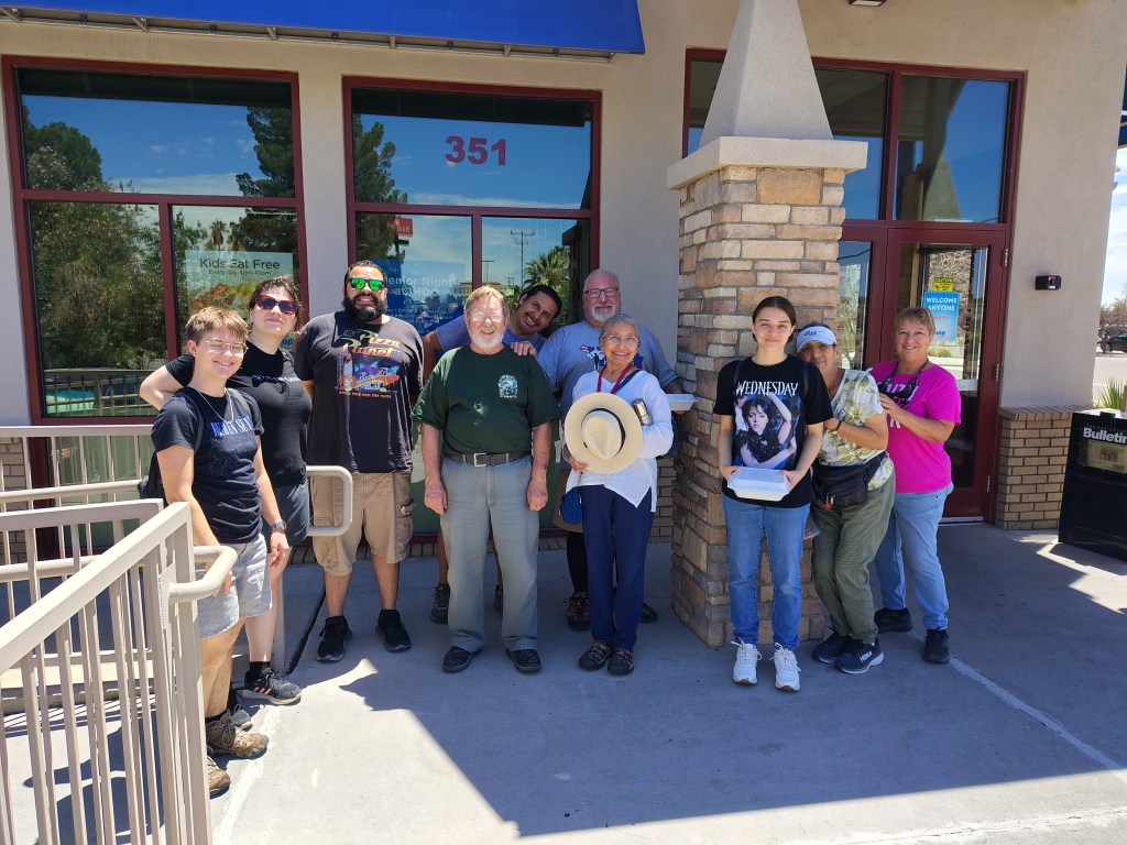 A group of diverse individuals stands outside a building, smiling and posing for a photo together.